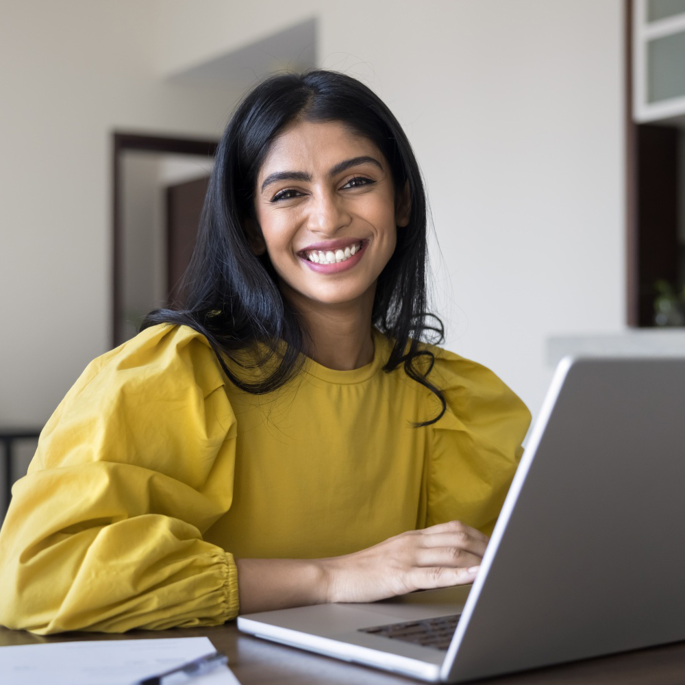 Smiling Indian CELPIP test taker with a laptop